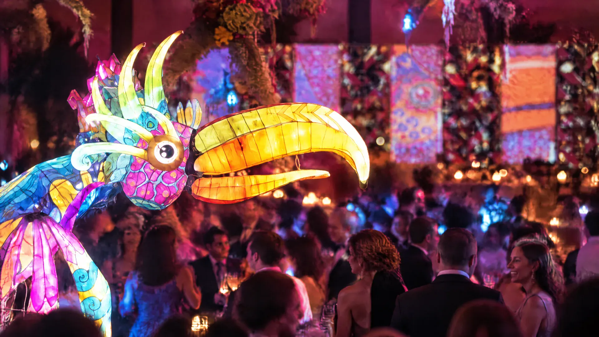 Escultura de tucán iluminada sobre una fiesta con mapping en el techo